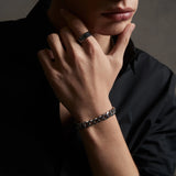 Person wearing a bracelet and ring with a dark background